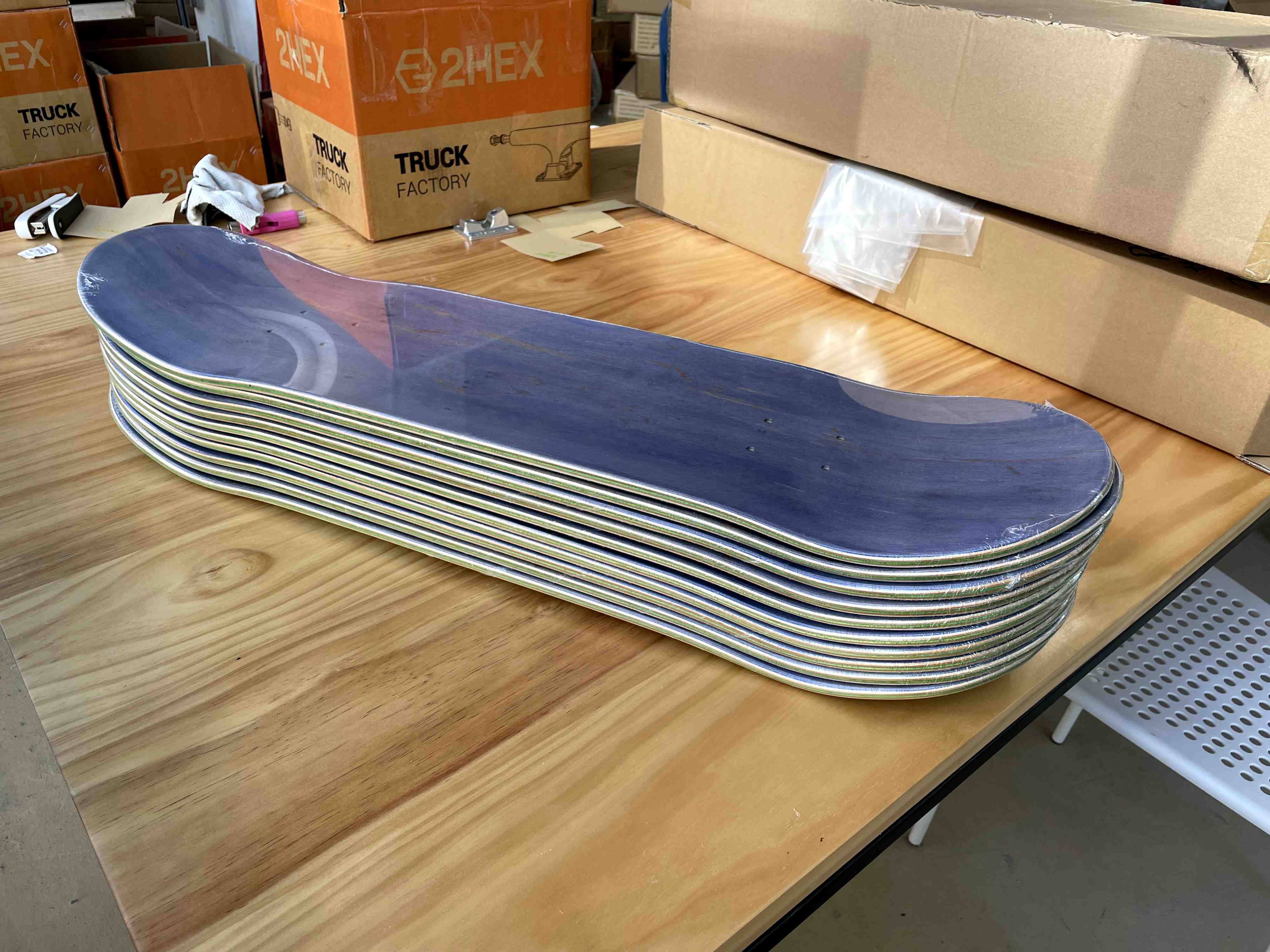 finished, shrink wrapped, blank decks at 2hex skateboard factory. blue top veneers, green centers.